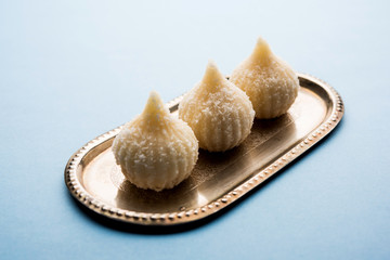Sweet Modak made using coconut, khoya and sugar. Popular Maharashtrian recipe offered to lord Ganesha in Ganesh Festival. Served in a plate. Selective focus