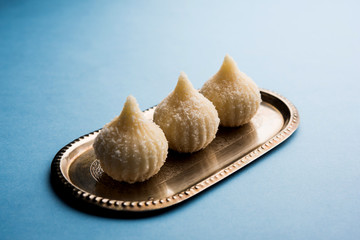 Sweet Modak made using coconut, khoya and sugar. Popular Maharashtrian recipe offered to lord Ganesha in Ganesh Festival. Served in a plate. Selective focus