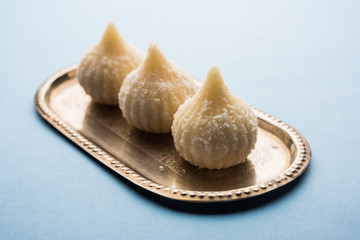 Sweet Modak made using coconut, khoya and sugar. Popular Maharashtrian recipe offered to lord Ganesha in Ganesh Festival. Served in a plate. Selective focus
