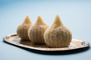 Sweet Modak made using coconut, khoya and sugar. Popular Maharashtrian recipe offered to lord Ganesha in Ganesh Festival. Served in a plate. Selective focus
