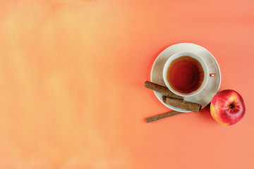 warm color background with hot cinnamon and aplle flavour tea in a white porcelain cup - obrazy, fototapety, plakaty