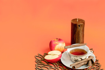 Autumn afternoon hot tea, apple and cinnamon flavour, orange background - obrazy, fototapety, plakaty