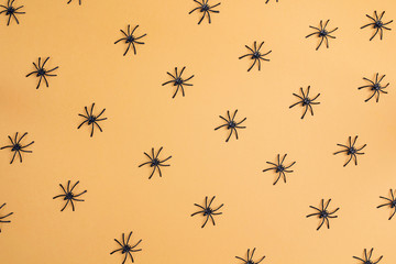 Halloween background with decorative spiders on orange backdrop.