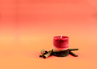 Red and brown candle with cinnamon on a orange autumn background - obrazy, fototapety, plakaty