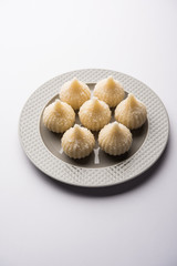Sweet Modak made using coconut, khoya and sugar. Popular Maharashtrian recipe offered to lord Ganesha in Ganesh Festival. Served in a plate. Selective focus