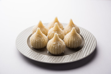 Sweet Modak made using coconut, khoya and sugar. Popular Maharashtrian recipe offered to lord Ganesha in Ganesh Festival. Served in a plate. Selective focus