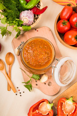 Tomato sauce (ketchup, adzhika) and vegetables on a beige table. Home preservation.