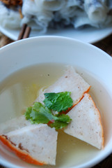 Banh cuon-vietnamese steamed rice rolls with minced meat inside  and pieces of vietnamese ham accompanied by bowl of fish sauce.