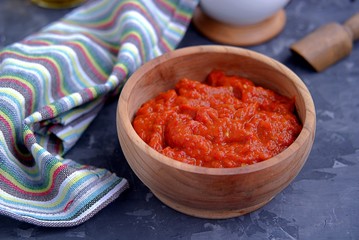 Aivar, vegetable dip or a snack of roasted red sweet peppers and eggplants in a wooden bowl on a dark gray background. Serbian cuisine.
