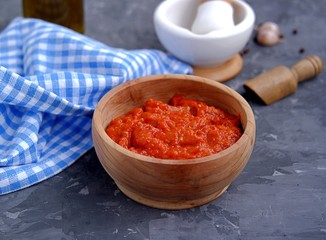 Aivar, vegetable dip or a snack of roasted red sweet peppers and eggplants in a wooden bowl on a dark gray background. Serbian cuisine.