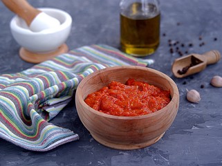 Aivar, vegetable dip or a snack of roasted red sweet peppers and eggplants in a wooden bowl on a dark gray background. Serbian cuisine.