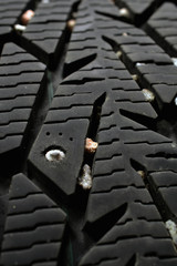 Used snow tire with metal studs close up. Vertical background image.