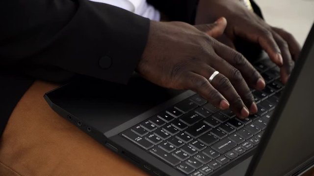 Man working outdoors on a laptop from African ethnicity. close up shot