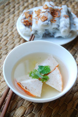 Banh cuon-vietnamese steamed rice rolls with minced meat inside  and pieces of vietnamese ham accompanied by bowl of fish sauce.