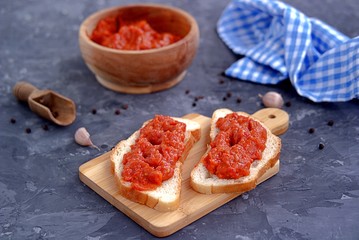 Thin open sandwiches with aivar, snack from baked sweet red pepper and eggplant on white bread. Serbian cuisine.