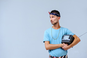 fashionable man in bright pants, with a small TV in his hands, the manifestation of emotions surprise scream irritability, gestures with hands a place for the text