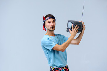 fashionable man in bright pants, with a small TV in his hands, the manifestation of emotions surprise scream irritability, gestures with hands a place for the text