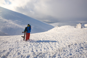 Adventurer, with backpack and snowboard in his hands