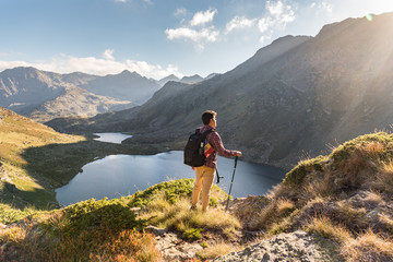 Men travel man standing on high mountain, hiking trip. Tristaina high mountain lakes in Pyrenees. Andorra