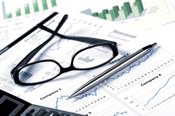 Glasses, Pen And Calculator On Financial Graphs Close-up