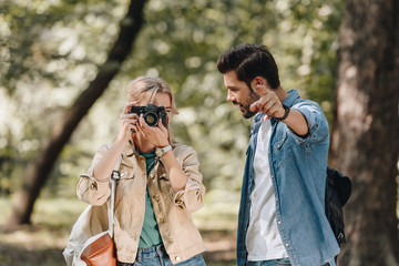 portrait of couple of young travelers with photo camera taking picture in park