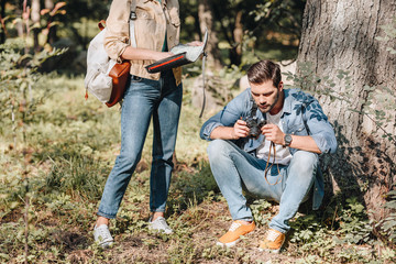 partial view of couple of travelers with map and photo camera in park