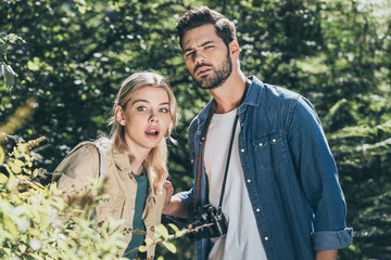 portrait of shocked couple of tourists with photo camera in park