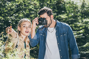 portrait of couple of tourists with photo camera taking picture in park