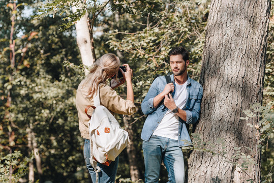 woman taking picture of stylish boyfriend in autumn park