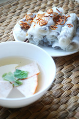 Banh cuon-vietnamese steamed rice rolls with minced meat inside  and pieces of vietnamese ham accompanied by bowl of fish sauce.