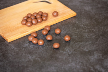 round chocolate candies lie on a wooden board on a gray stone background