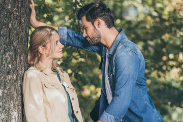 side view of young romantic couple looking at each other in autumn park