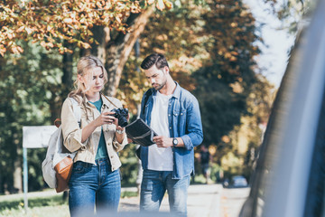 portrait of young tourists with photo camera and map standing on street