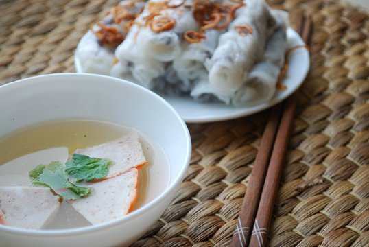 Banh cuon-vietnamese steamed rice rolls with minced meat inside  and pieces of vietnamese ham accompanied by bowl of fish sauce.