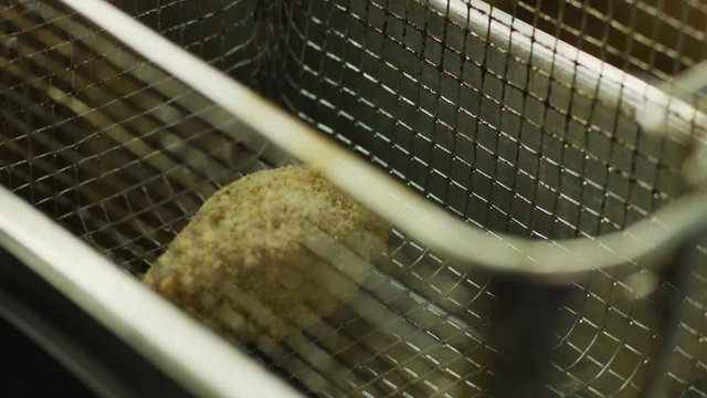 Woman putting food in a deep fryer in a slow motion close up