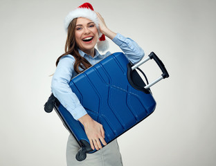 Happy woman wearing Santa Christmas hat holding blue suitcase.