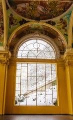 Window and wall painting in the building of the Cross Spring (krizovy pramen). Spa center of small west Bohemian spa town Marianske Lazne (Marienbad) in winter with snow - Czech Republic.