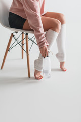 Crop woman on chair with bottle of water