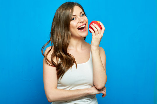 Smiling woman with healthy teeth holding red apple.