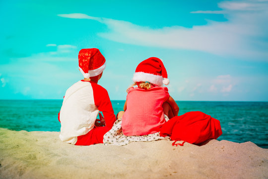 little boy and girl with presents celebrating christmas on tropical beach