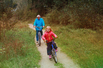 active senior grandmother with granddaughter riding bikes in nature
