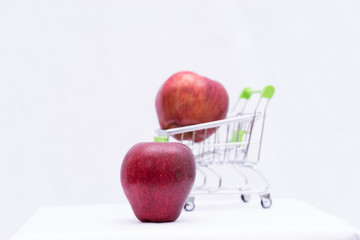 Red apple fruit on blurred apple in toy cart on white backgrond,