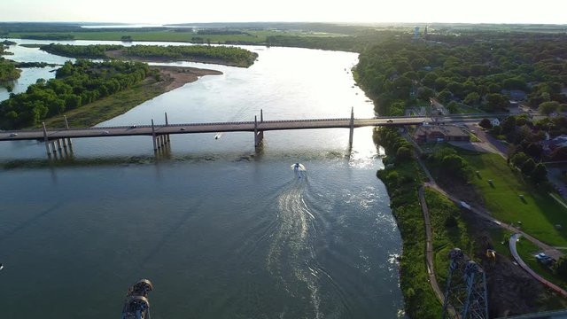 Aerial shot following a boat going under a bridge at sunset in 4K