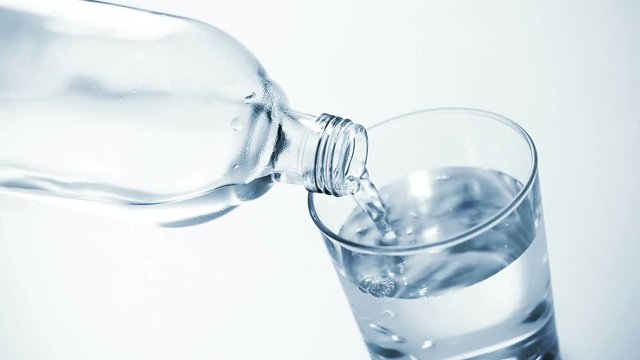 Looping cinemagraph, pouring clear water into glass on blue background