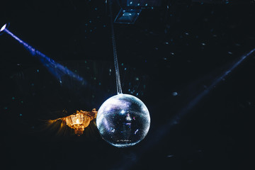 Disco ball with lights shining from the sides in a club