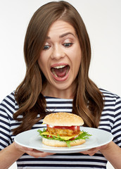 Happy emotional woman holding burger on white plate.