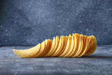 A stack of crispy chips on a gray dark table. Snack.