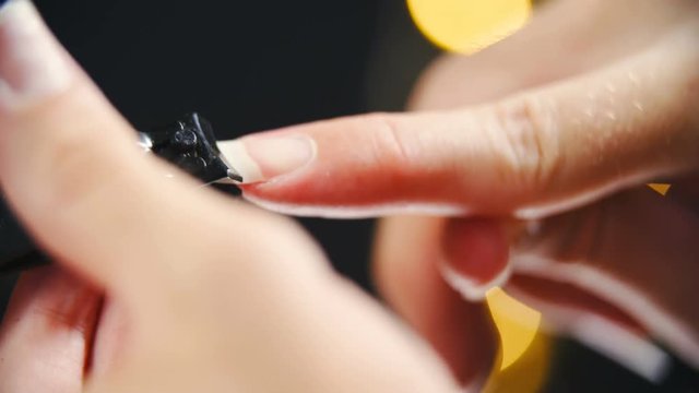 Use Nail Clipper Cut The Long Nails close-up 4K. Long shot of person beautiful long fingernail in focus while clipping with black clipper in slow motion on a black background.