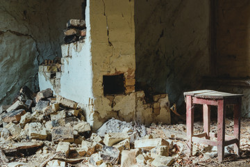 abandoned building with broken brick wall and wooden chair with dust