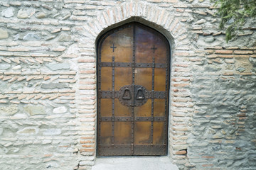 Ancient wooden framed metal door in a brick wall